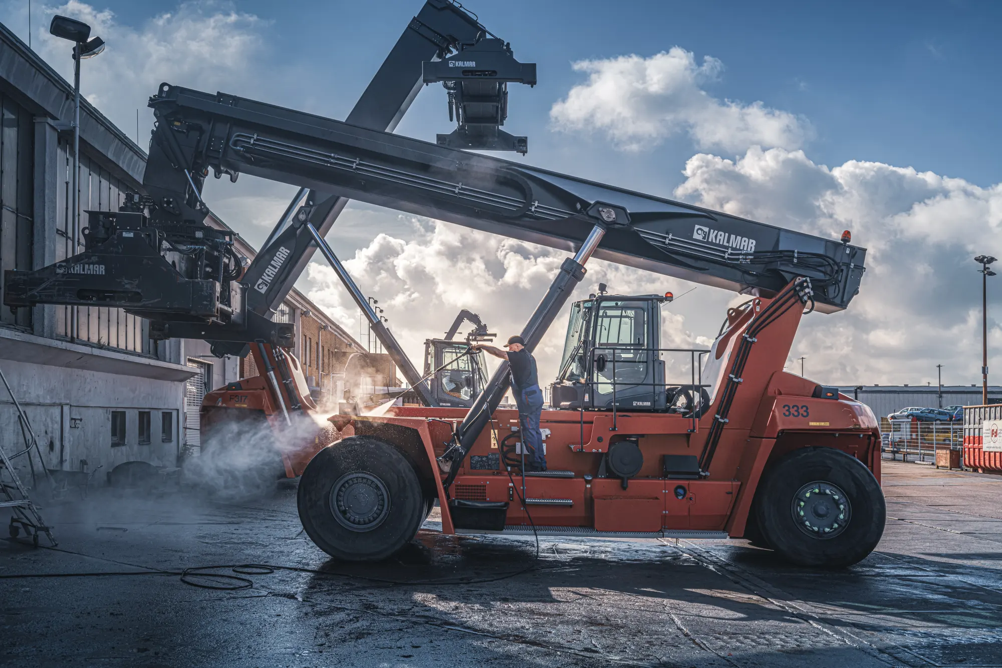 Orangefarbener Reachstacker mit angehobenem Ausleger auf dem Terminal