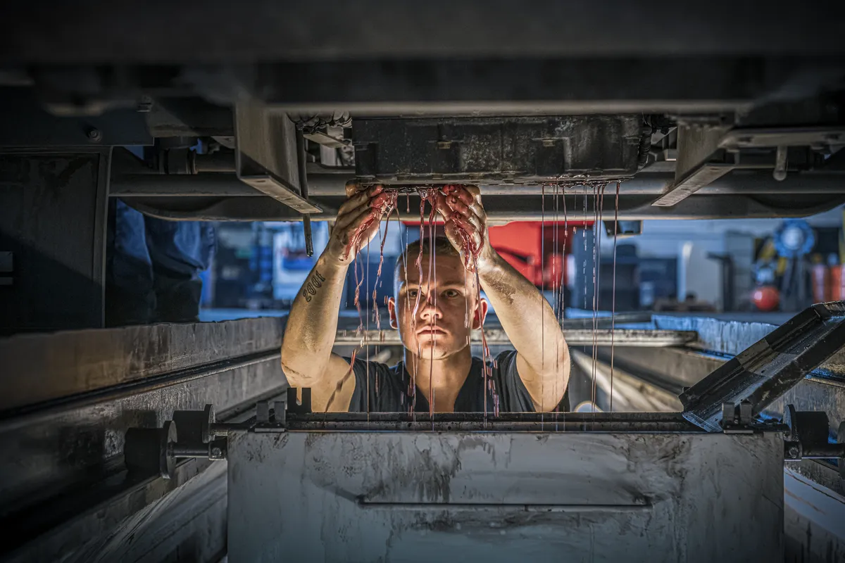 Mechaniker arbeitet von unten an der Unterseite eines Fahrzeugs