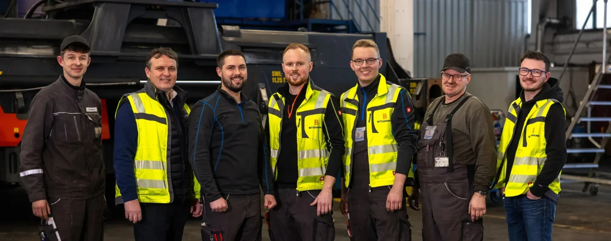 Teambild: Mitarbeitende von Bittermann in Warnwesten in der Werkstatt
