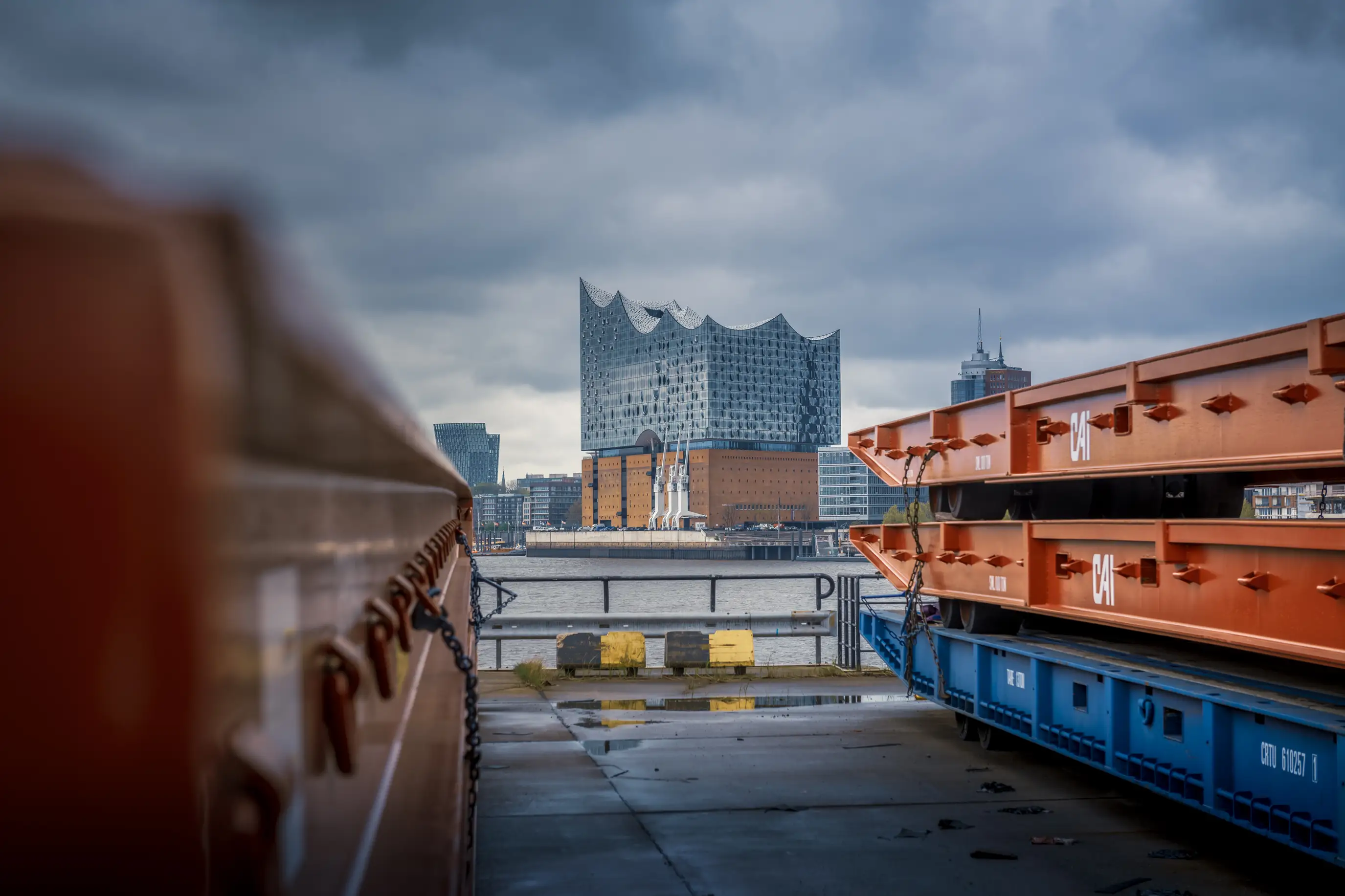 Blick im Hamburger Hafen auf die Elbphilharmonie, davor orangefarbene Auflieger