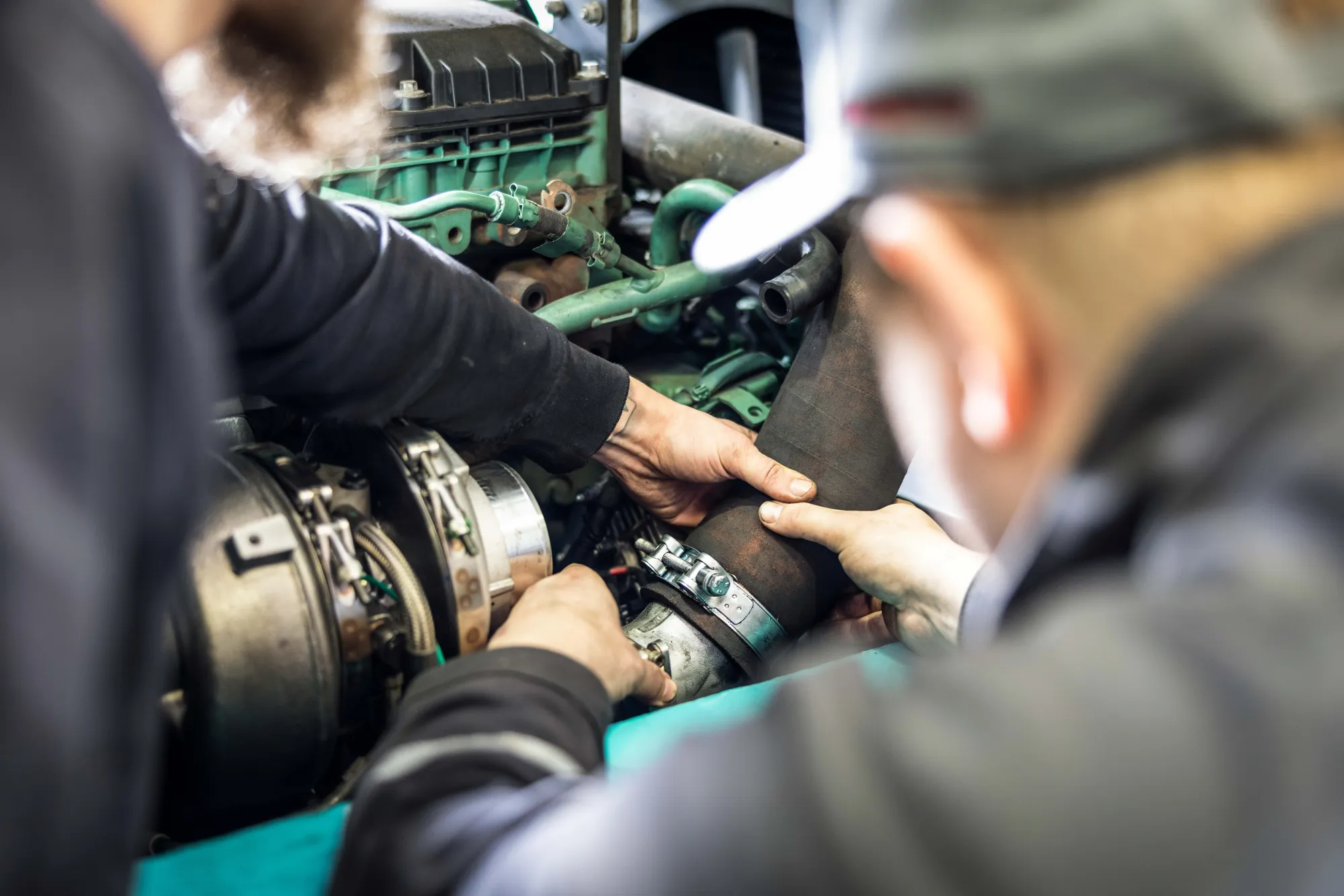 Hände zweier Mechaniker bei Arbeiten an einem Motor