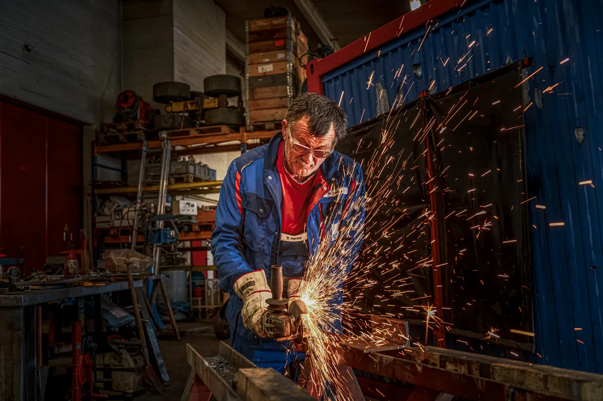 Metallarbeiter beim Trennschleifen in der Werkstatt, Funken sprühen